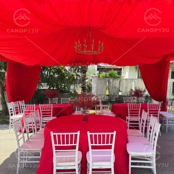 Red canopy with red tablecloths and white chairs for a festive event